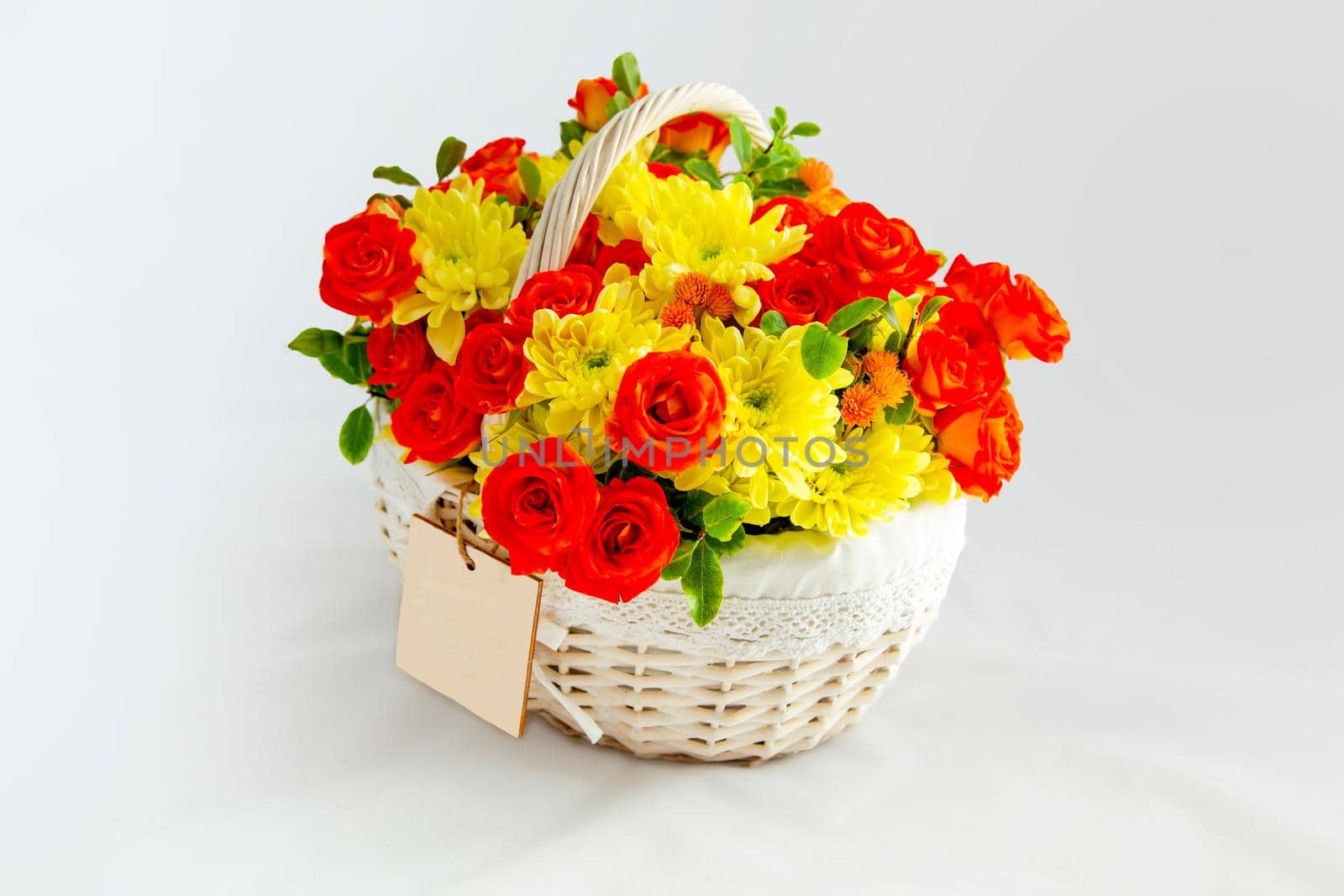 beautiful white basket with scarlet roses and yellow chrysanthemums. white background for cutting. card blank for the inscription copy space