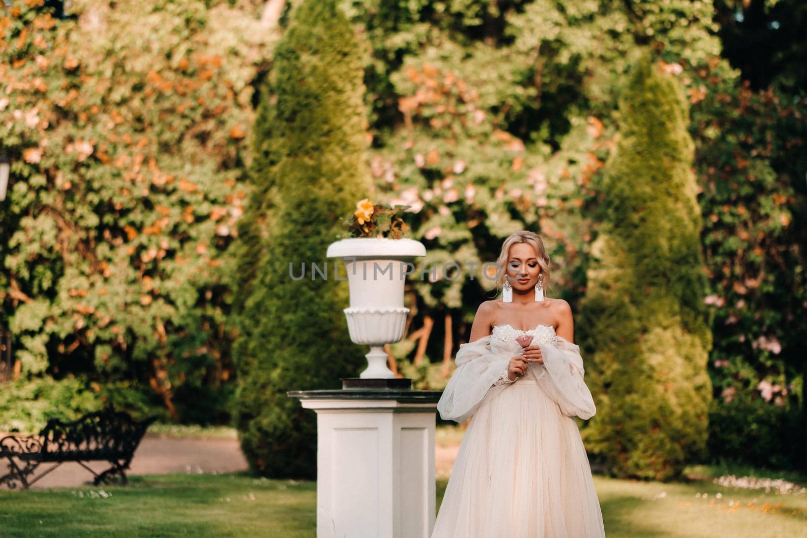 A beautiful bride in a luxurious wedding dress holds a rose and greenery on a green natural background. Portrait of a happy bride in a white dress, smiling against the background of a Park