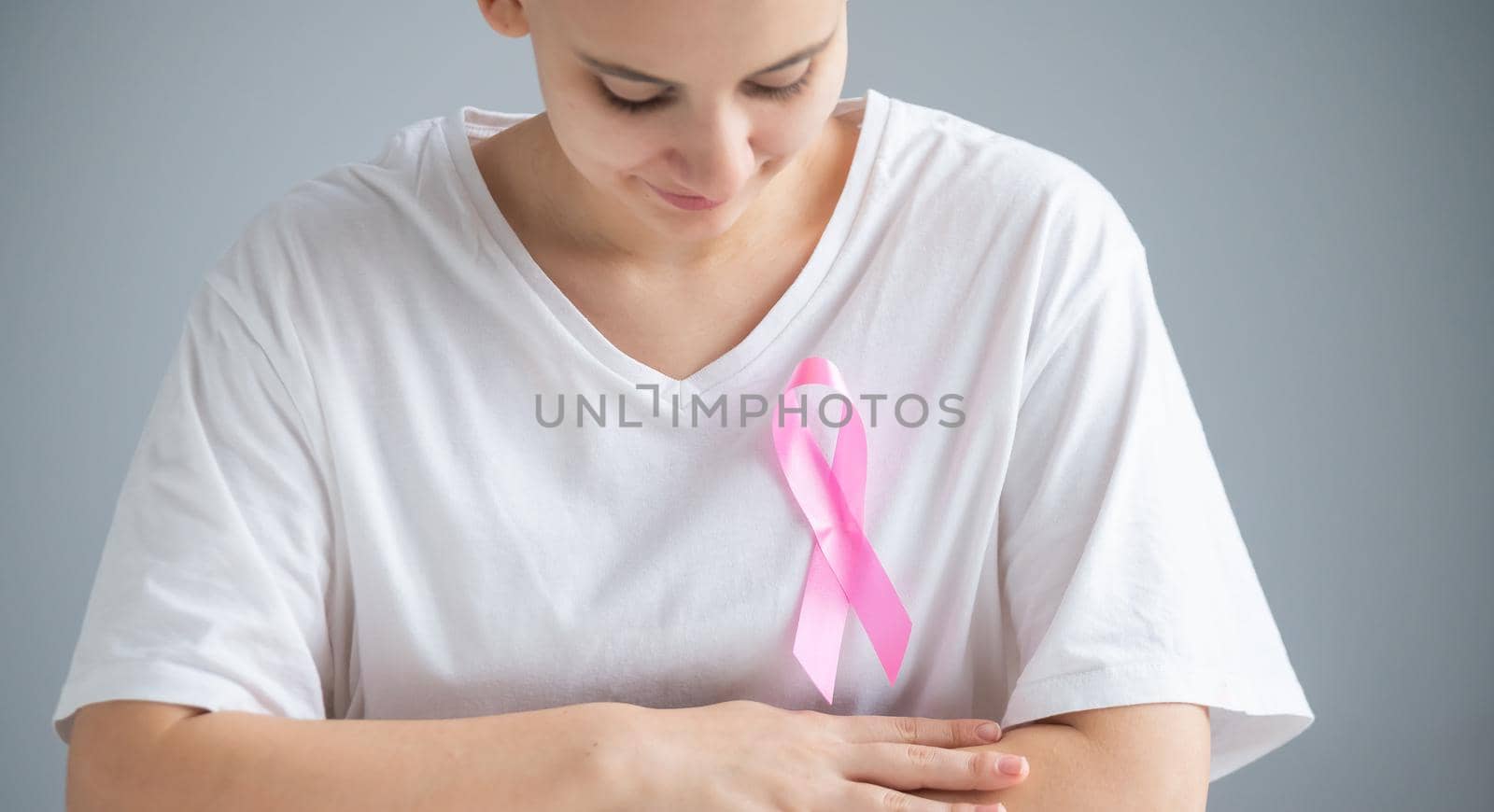 Woman with a pink ribbon on a white t-shirt as a symbol of breast cancer on a white background