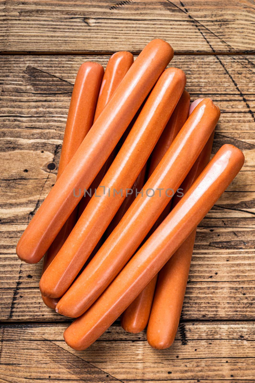 Raw frankfurter sausages on kitchen table. Wooden background. Top view.