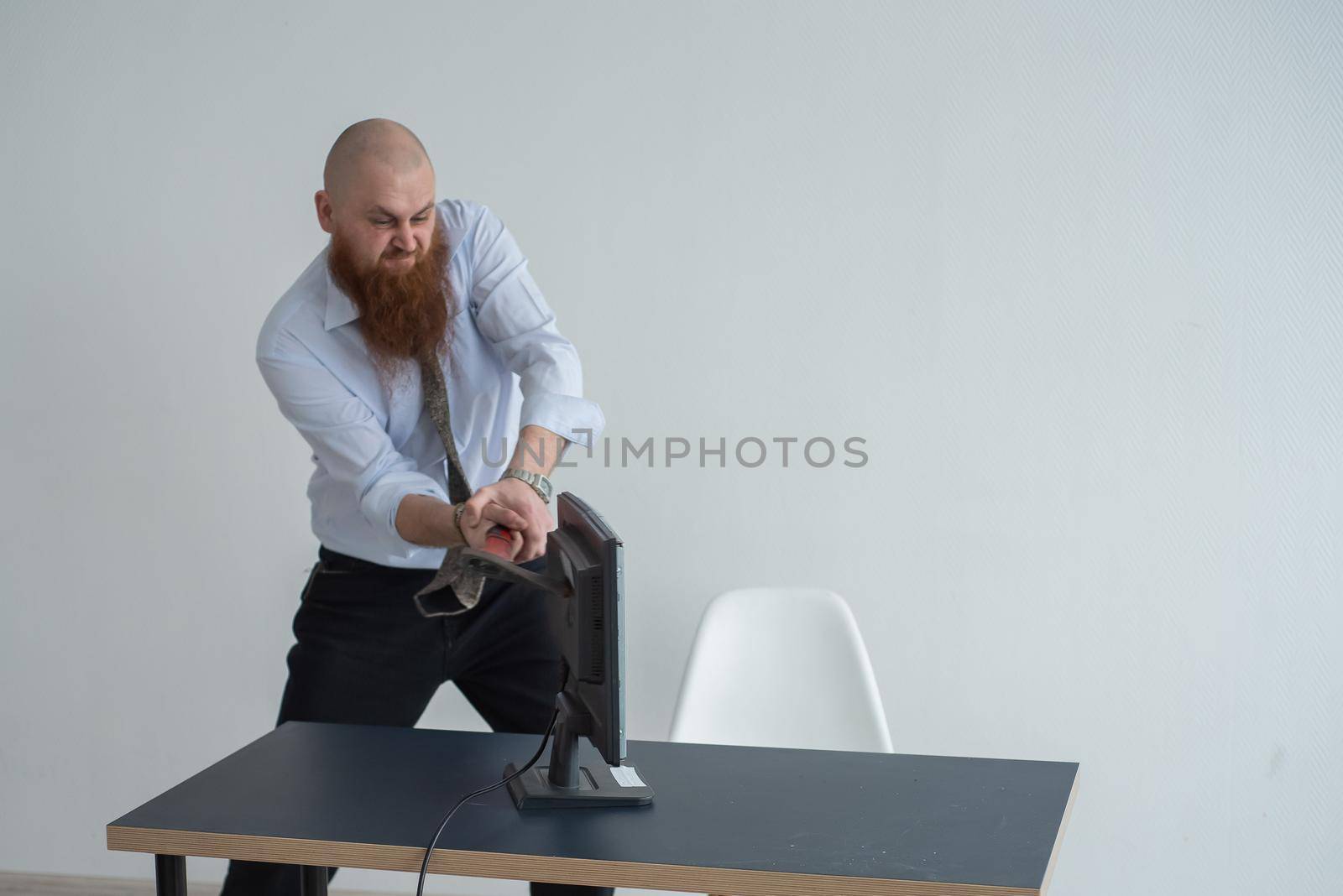 Stressed crazy businessman smashing his computer in office using ax problem concept. The man has problems at work and frustration. by mrwed54