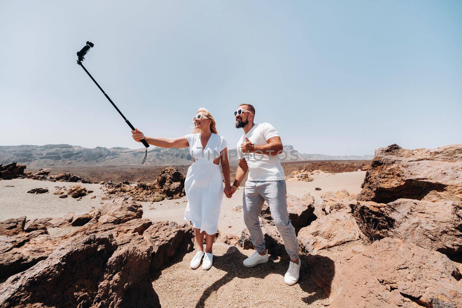 a stylish woman takes a selfie in the crater of the Teide volcano. Desert landscape in Tenerife. Teide National Park. Desert crater of the Teide volcano. Tenerife, Canary Islands.