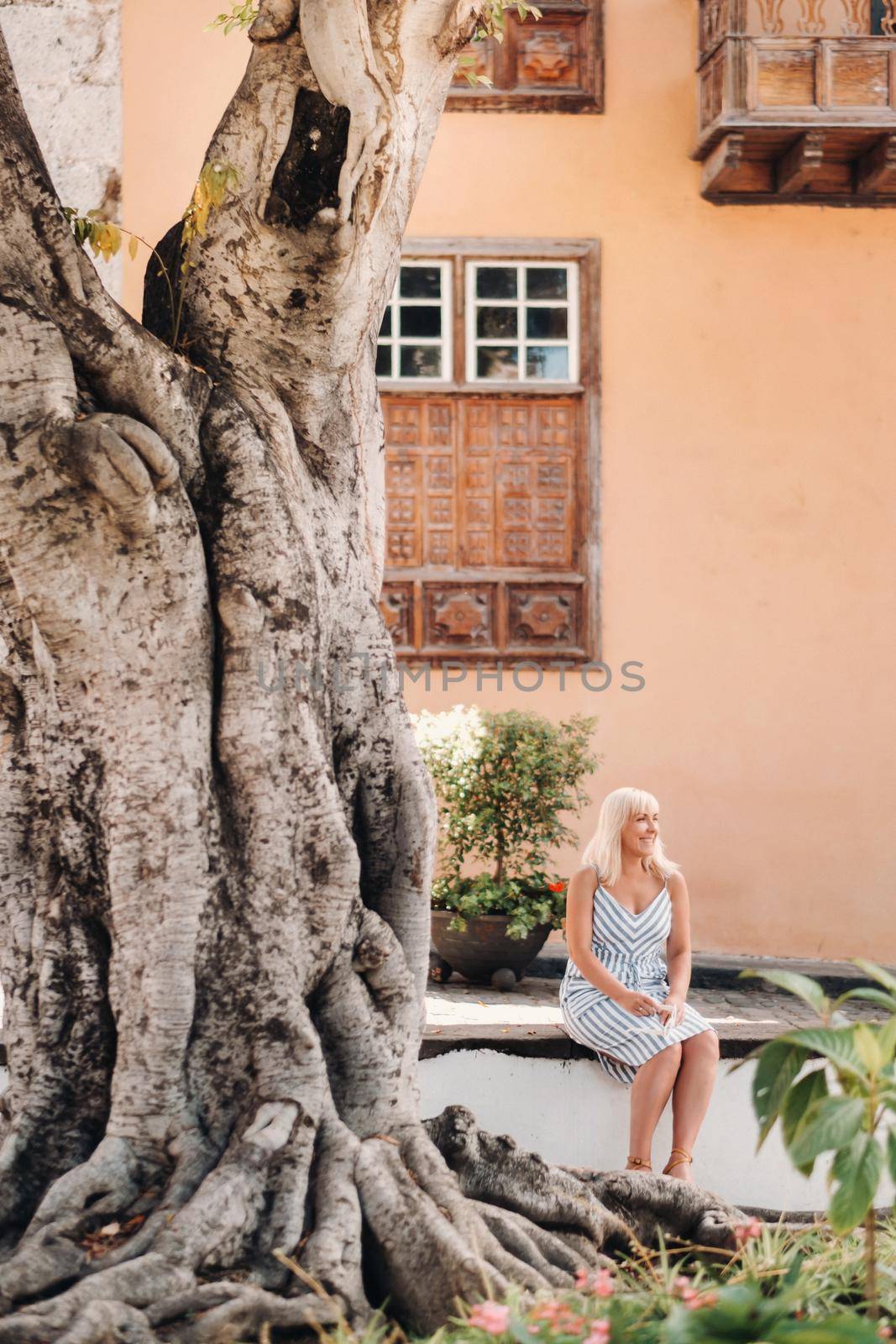 a blonde woman in a sundress sits on the street of the Old town of Garachico on the island of Tenerife.Spain, Canary Islands