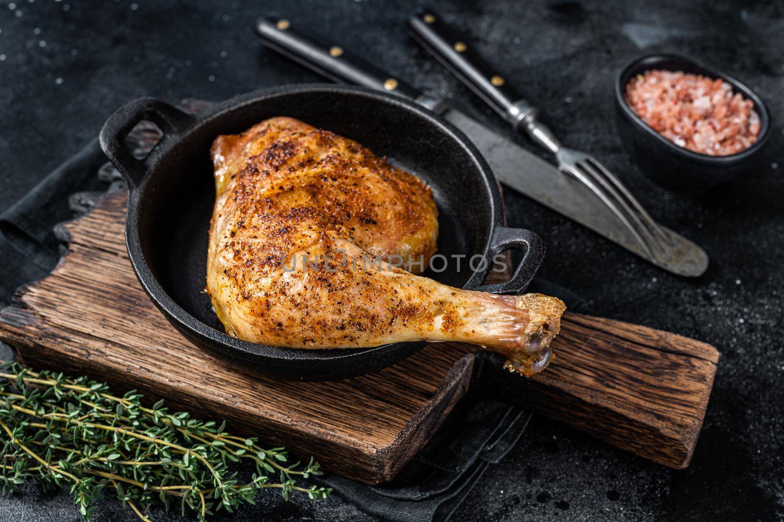 Fried bbq chicken leg in a pan. Black background. Top view by Composter