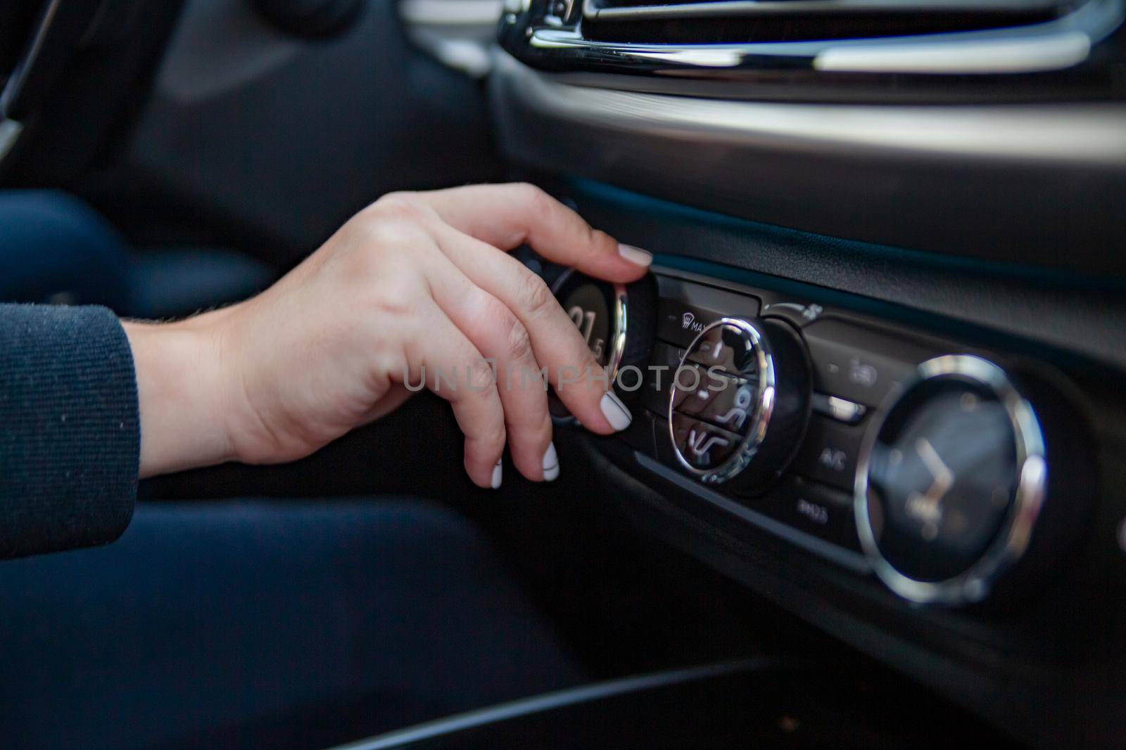 a woman's hand turns the knob for adjusting the climate control system in a modern premium car. setting a comfortable temperature in the car. travel by car. no face