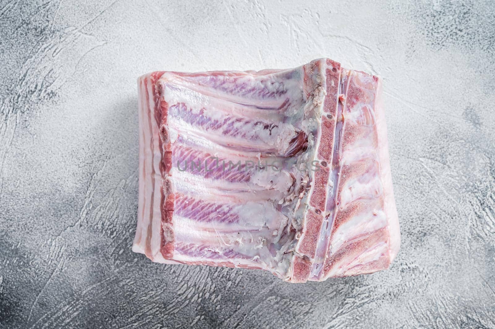 Raw whole rack of pork loin with ribs on kitchen table. White background. Top view by Composter