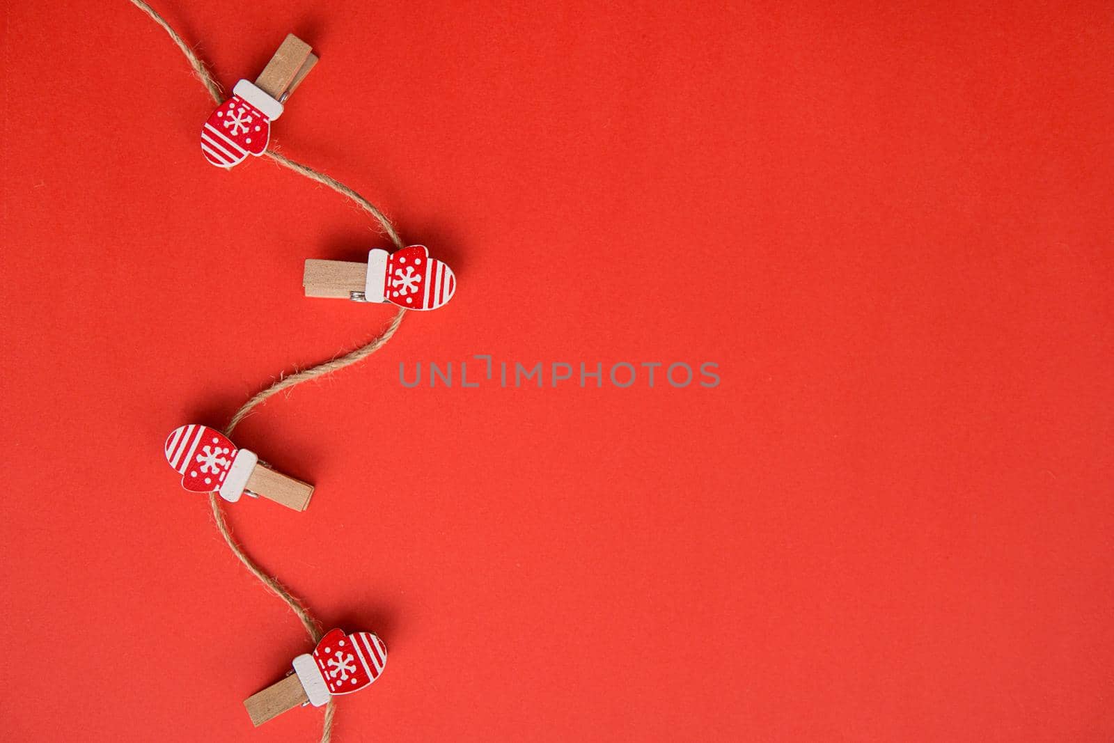 Christmas decorations decorative background. Decorative pins in the form of red gloves on a red background. Top view, minimalism, flat lay. Space for text.