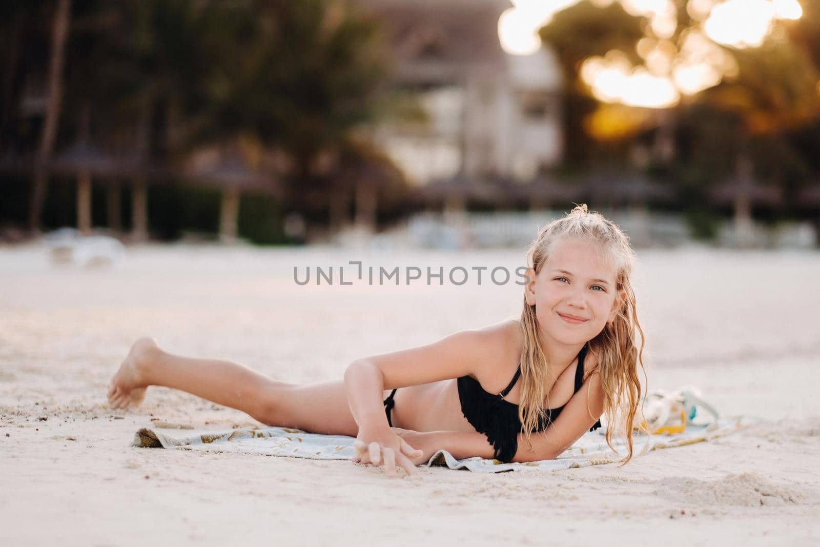 A charming little girl is lying on the beach and drawing on the sand.A little girl lies on the beach of the island of Mauritius.