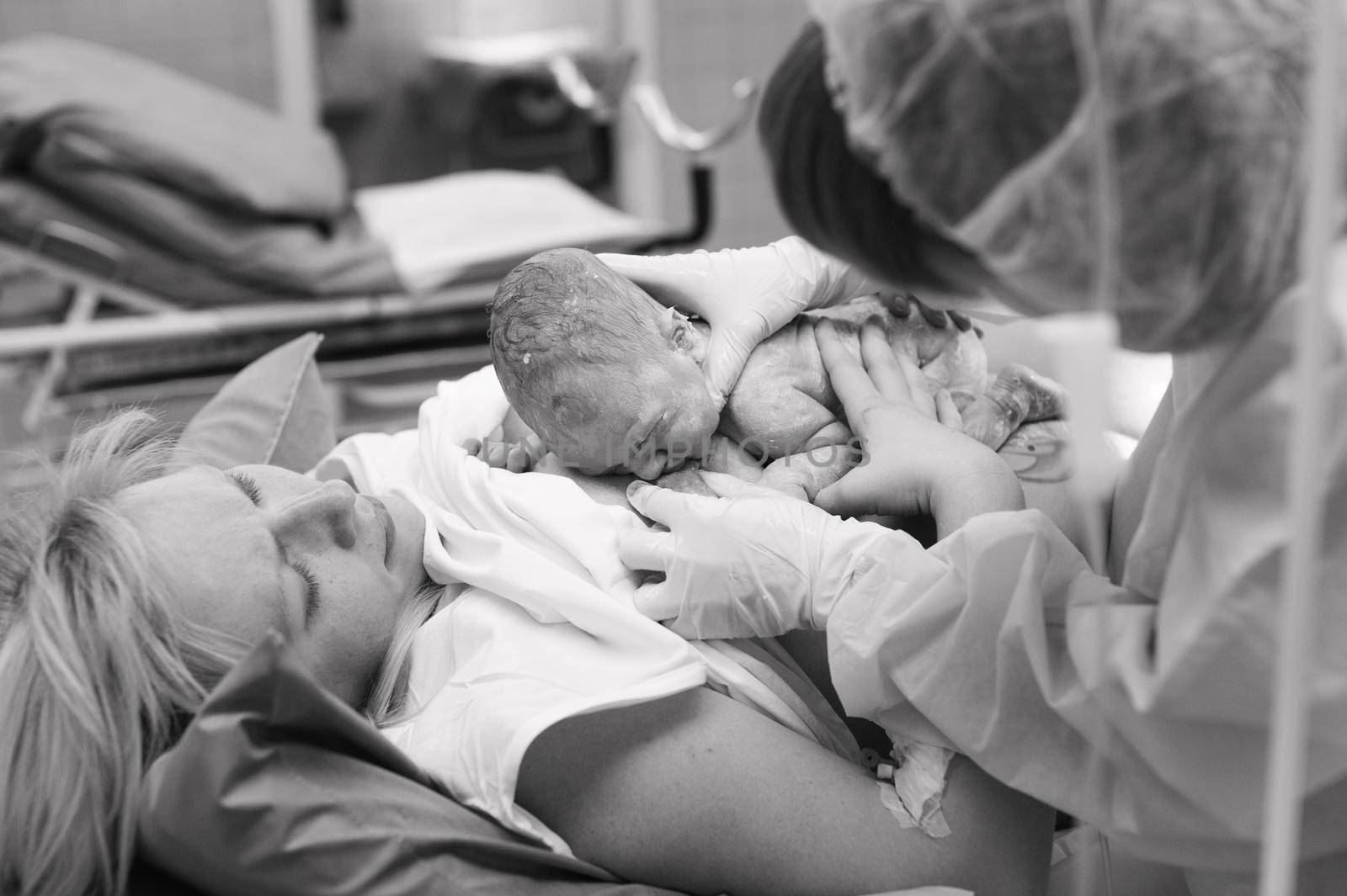 Close-up of a newborn feeding on the mother's breastbone in the maternity ward of a hospital, immediately after birth.Black and white photo by Lobachad