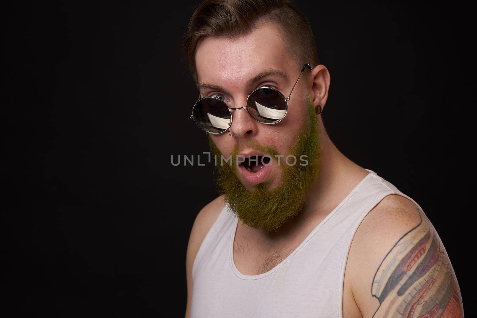 handsome man with tattoos on his arms fashion sunglasses dark background. High quality photo