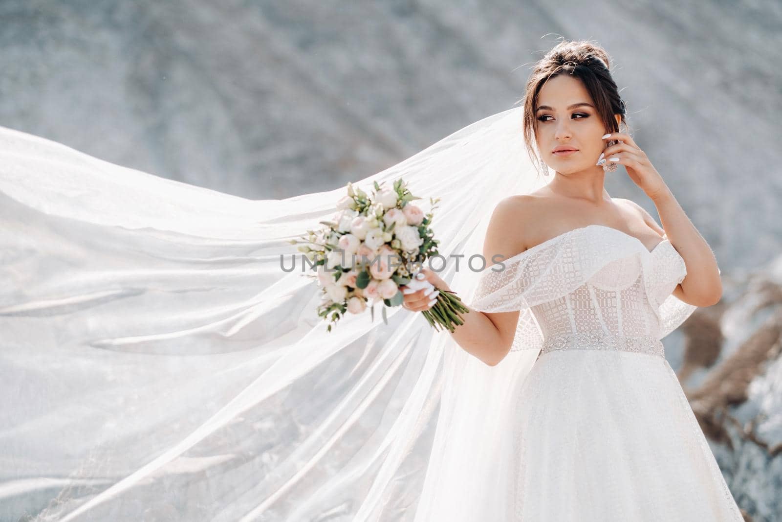 Beautiful bride in a wedding dress with a bouquet on the top of the salt mountains. A stunning young bride with curly hair . Wedding day. . Beautiful portrait of the bride without the groom. by Lobachad