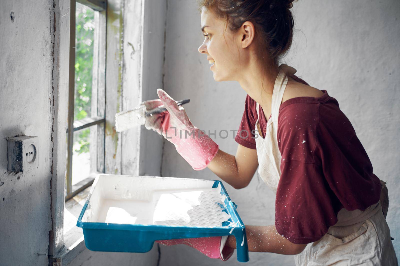 woman painter makes home repairs near window interior. High quality photo