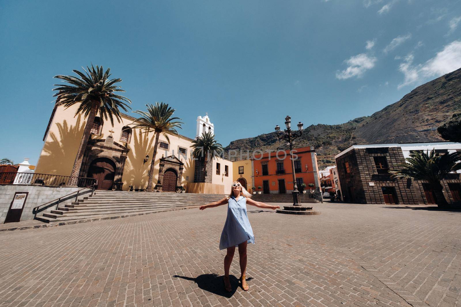 A girl in a blue dress walks through the Old town of Garachico on the island of Tenerife on a Sunny day.A tourist walks through the old town of Tenerife in the Canary Islands.Spain