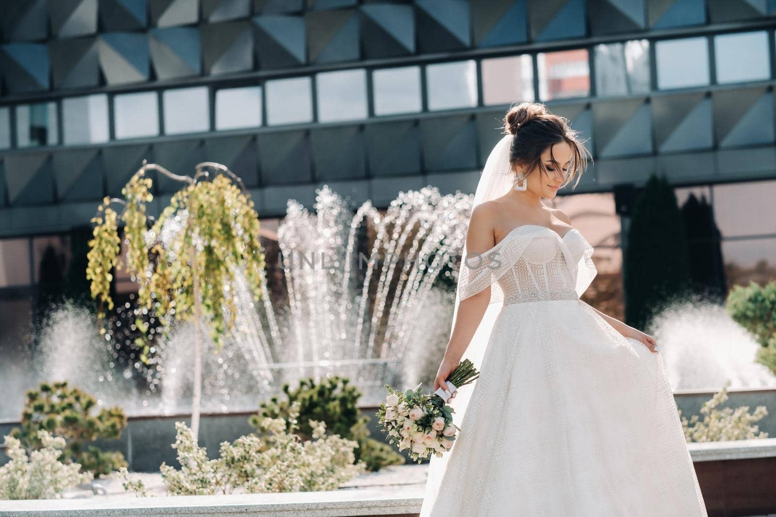 Portrait of the bride in the city near the fountain.A stunning young bride with curly hair . Wedding day. . Beautiful portrait of the bride without the groom. by Lobachad