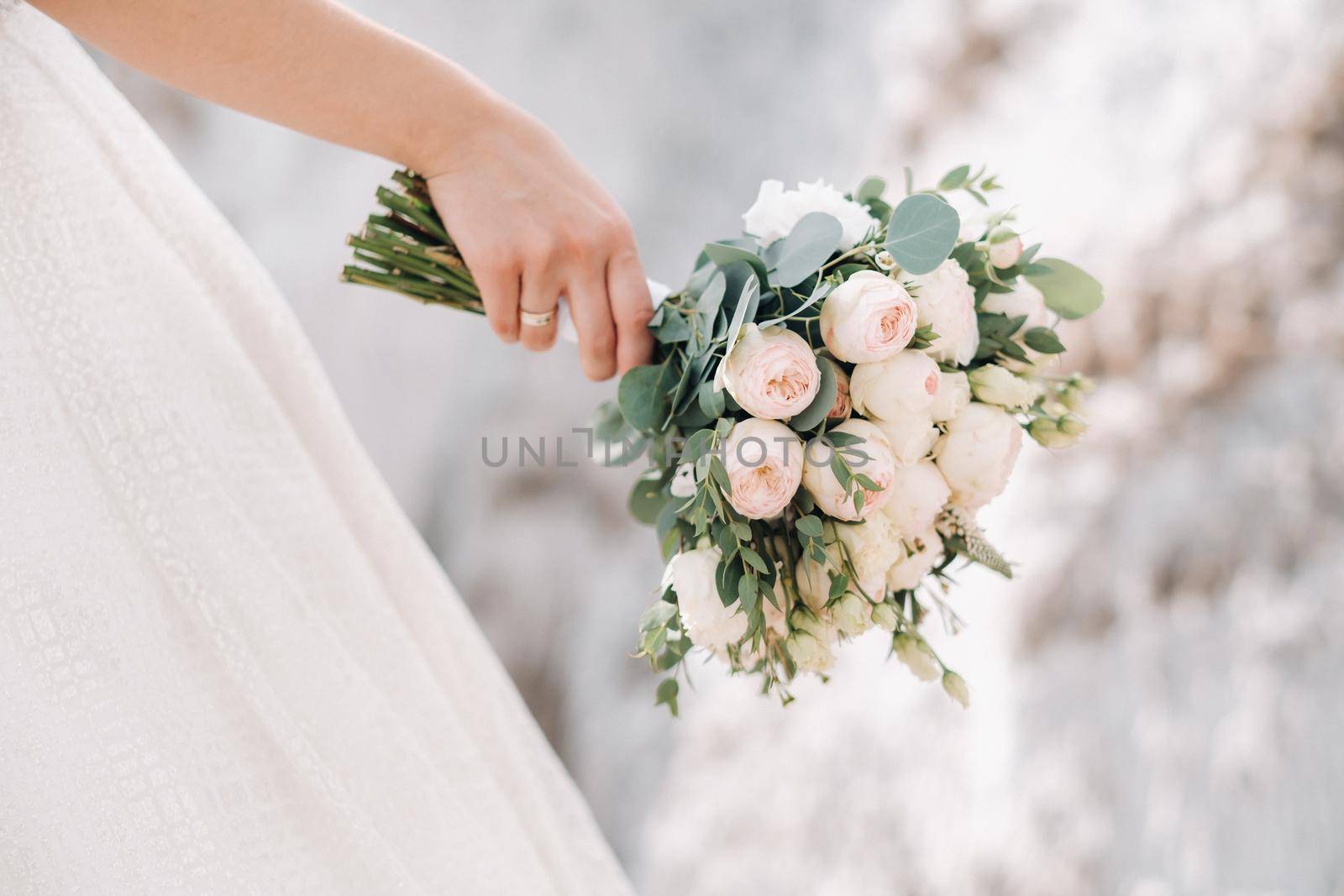 Beautiful bride is holding a wedding colorful bouquet. Beauty of colored flowers. Close-up bunch of florets. Bridal accessories. Female decoration for girl. Details for marriage and for married couple.