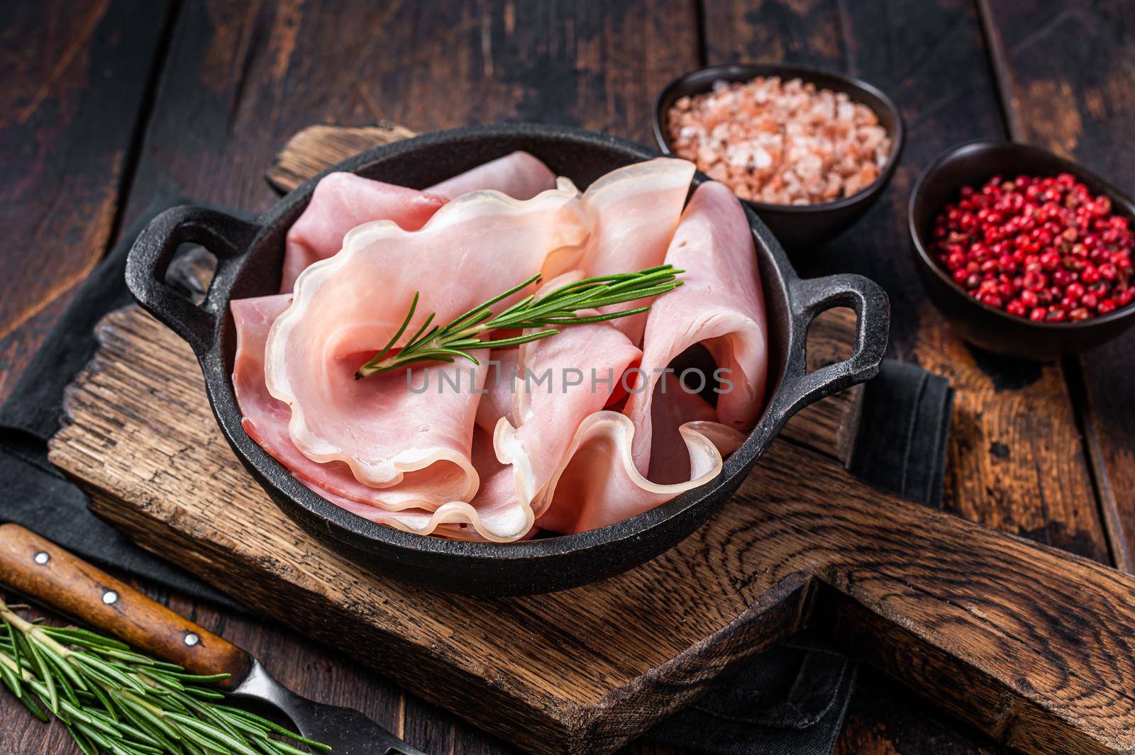 Prosciutto ham sliced in a pan. Dark wooden background. Top view.