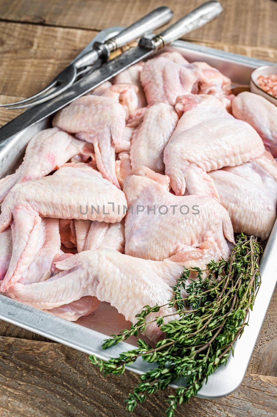 Fresh Raw chicken wings Poultry meat in a kitchen tray with herbs. Wooden background. Top view.