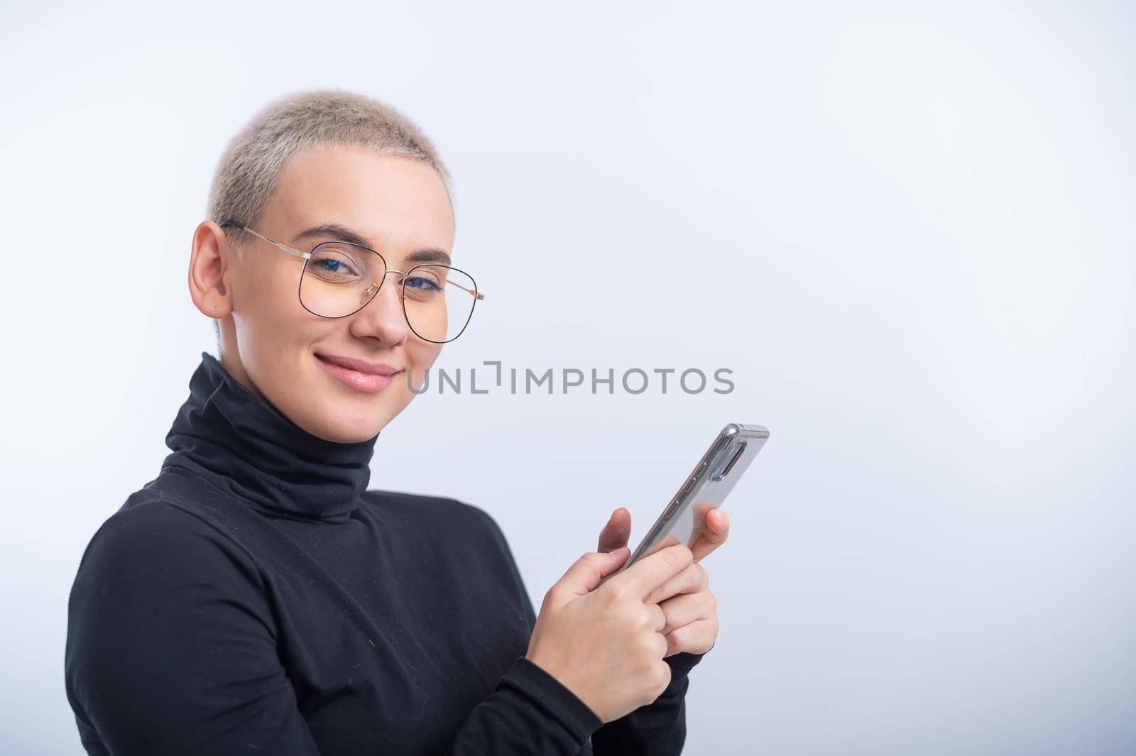 Young caucasian woman with short hair uses a smartphone on a white background. by mrwed54