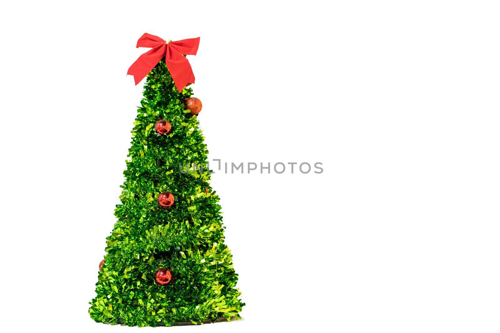 isolated artificial green christmas tree with red balls and bow, copy space