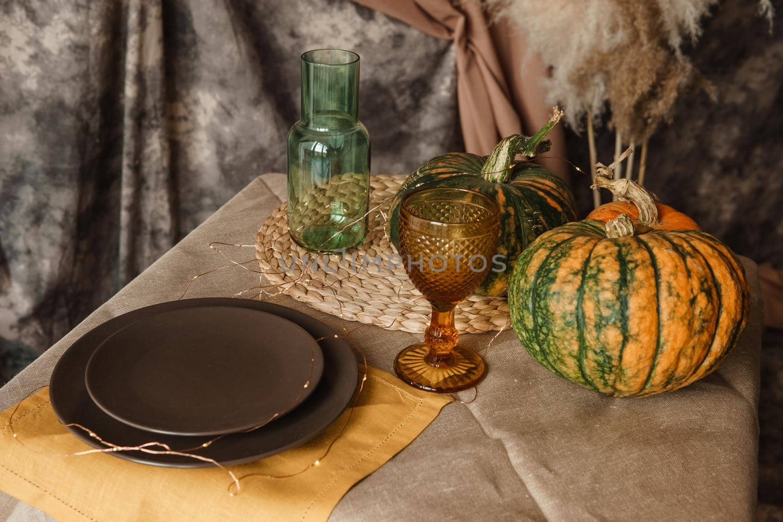 Autumn interior: a table covered with dishes, pumpkins, a relaxed composition of Japanese pampas grass. Interior in the photo Studio. Close - up of a decorated autumn table. by Annu1tochka
