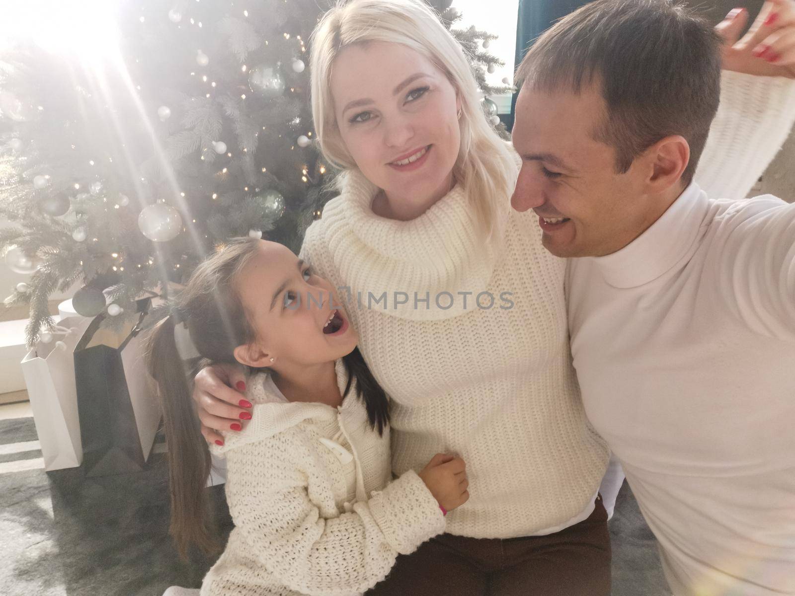 family, holidays, technology and people - smiling mother, father and little girl making selfie with camera over living room and christmas tree background