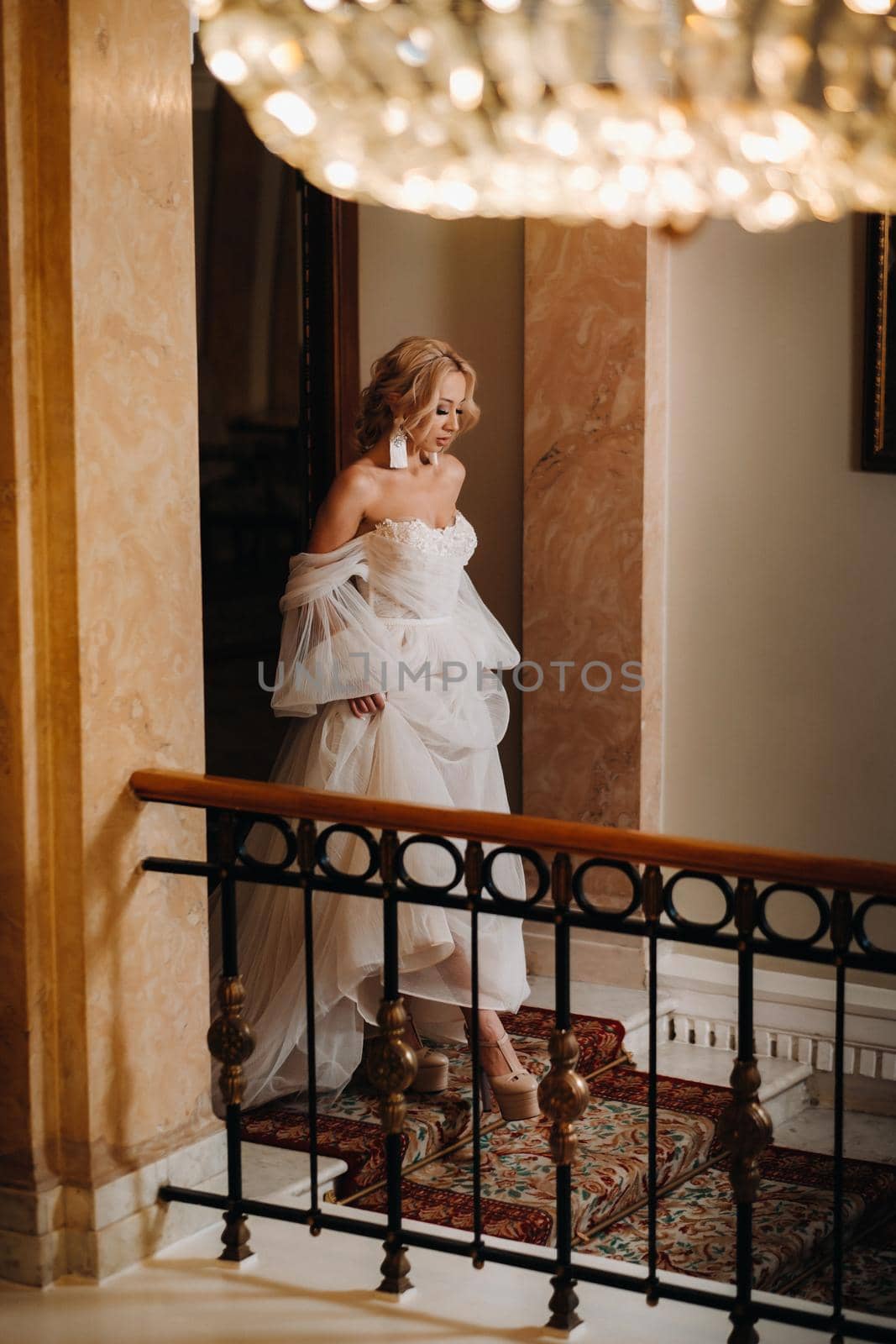 Portrait of a beautiful bride descending the stairs in the hall by Lobachad