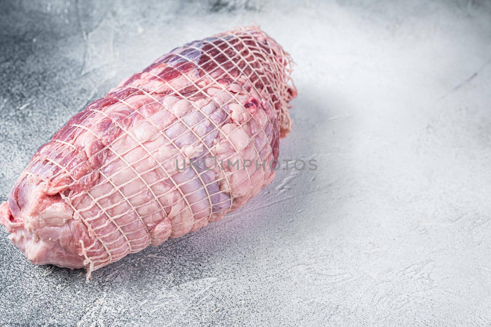 Boneless Leg of Lamb meat on butcher table. White background. Top view. Copy space.