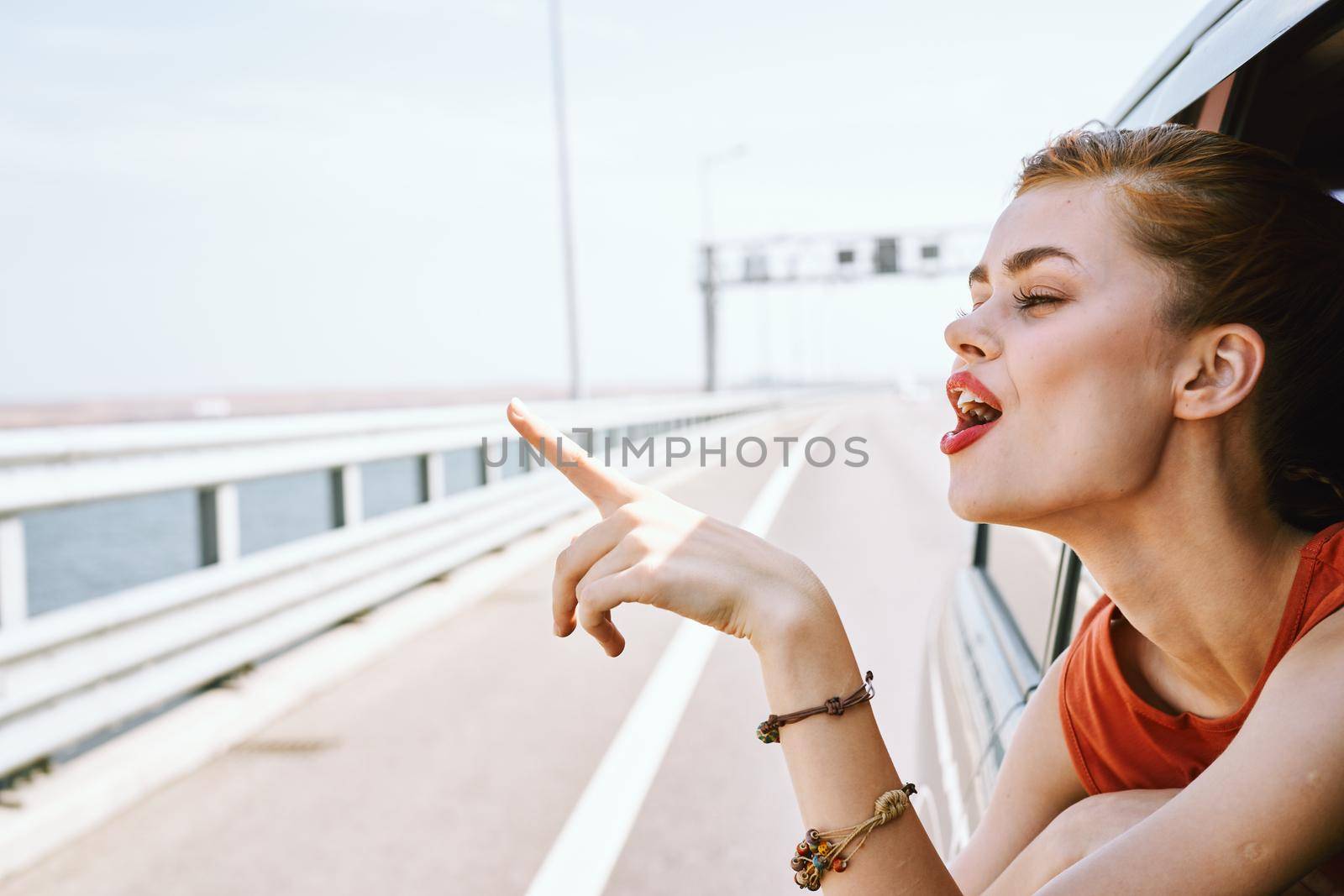 cheerful woman peeking out of the car window trip road travel. High quality photo