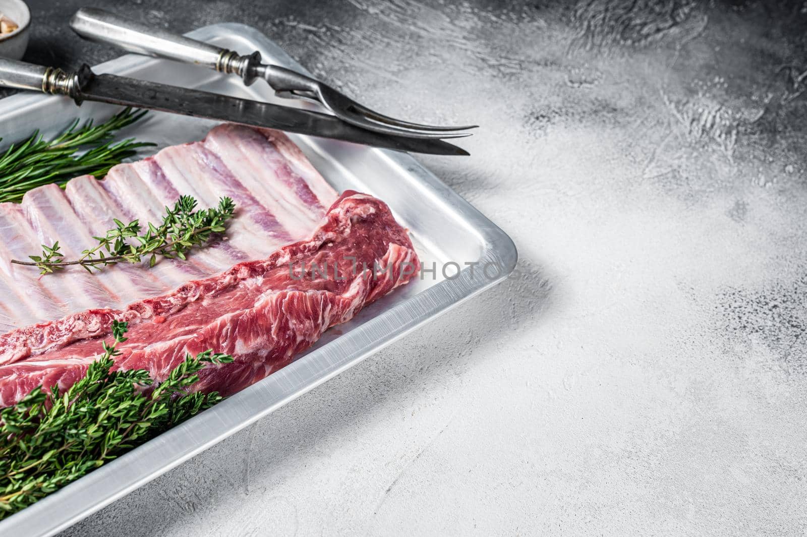 Raw uncooked rack of mutton lamb ribs in baking dish. White background. Top view. Copy space.