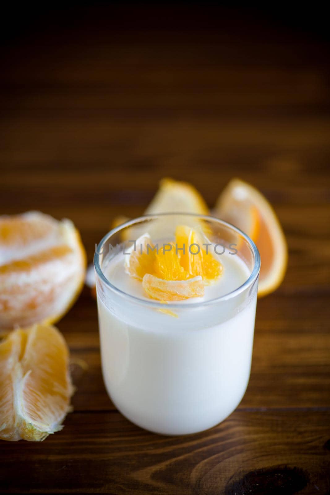 homemade sweet yogurt in a glass with oranges on a wooden table