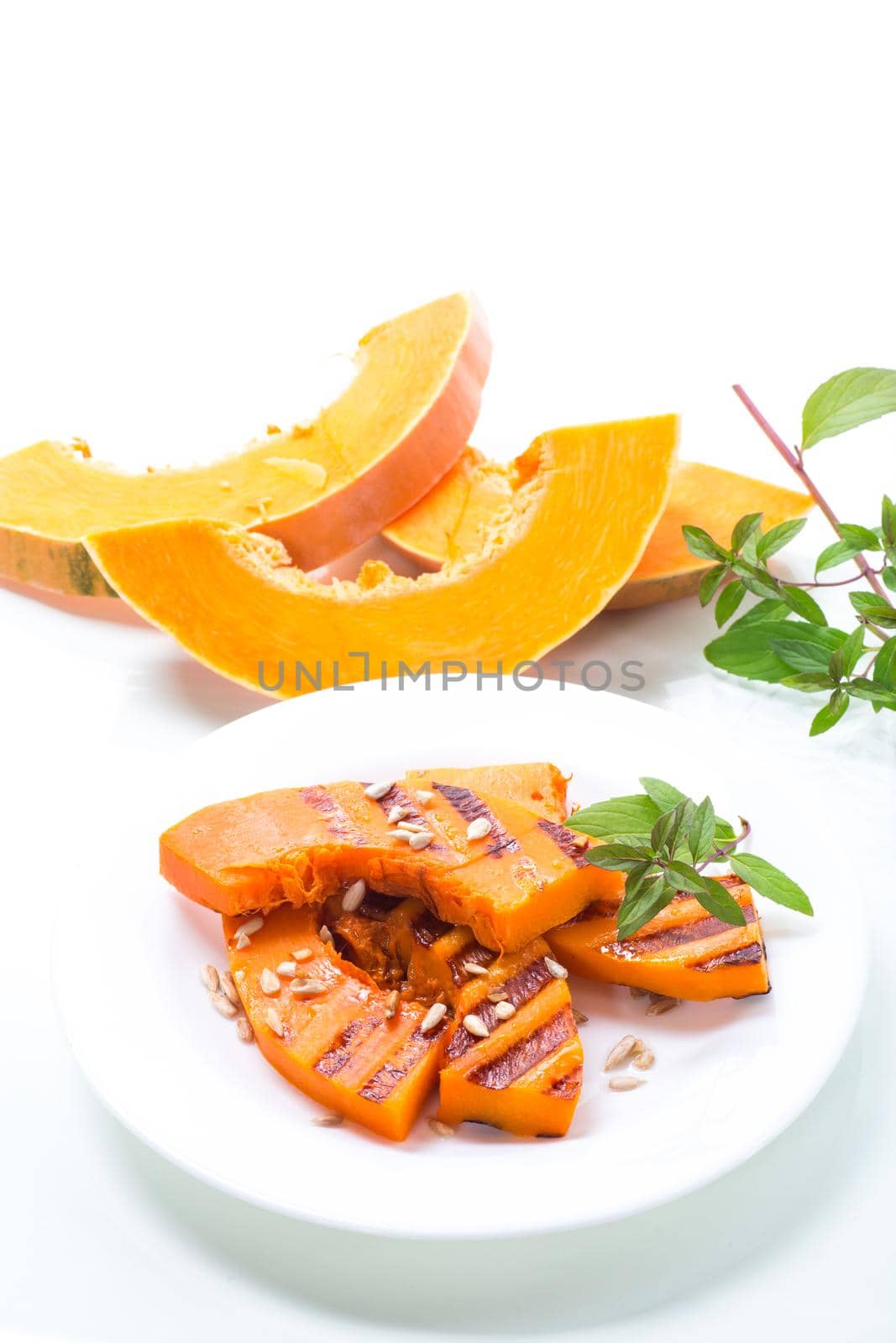 sweet baked grilled pumpkin with seeds in a plate isolated on white background
