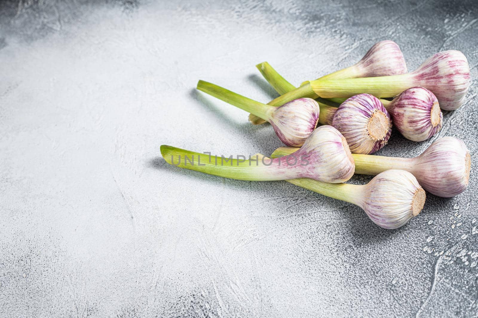 Fresh Spring young garlic bulbs on kitchen table. White background. Top view. Copy space by Composter