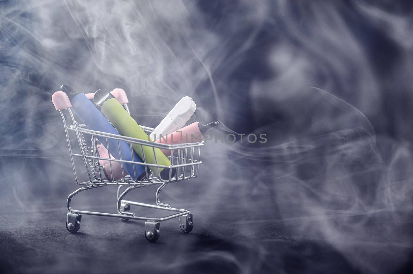 Disposable vapes in a shopping cart on a black background. Modern electronic cigarettes