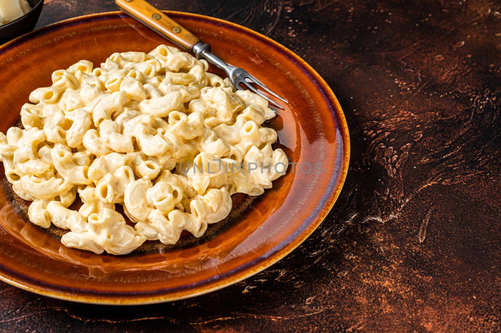 Macaroni Mac and cheese with Cheddar sauce in a plate. Dark background. Top view. Copy space.