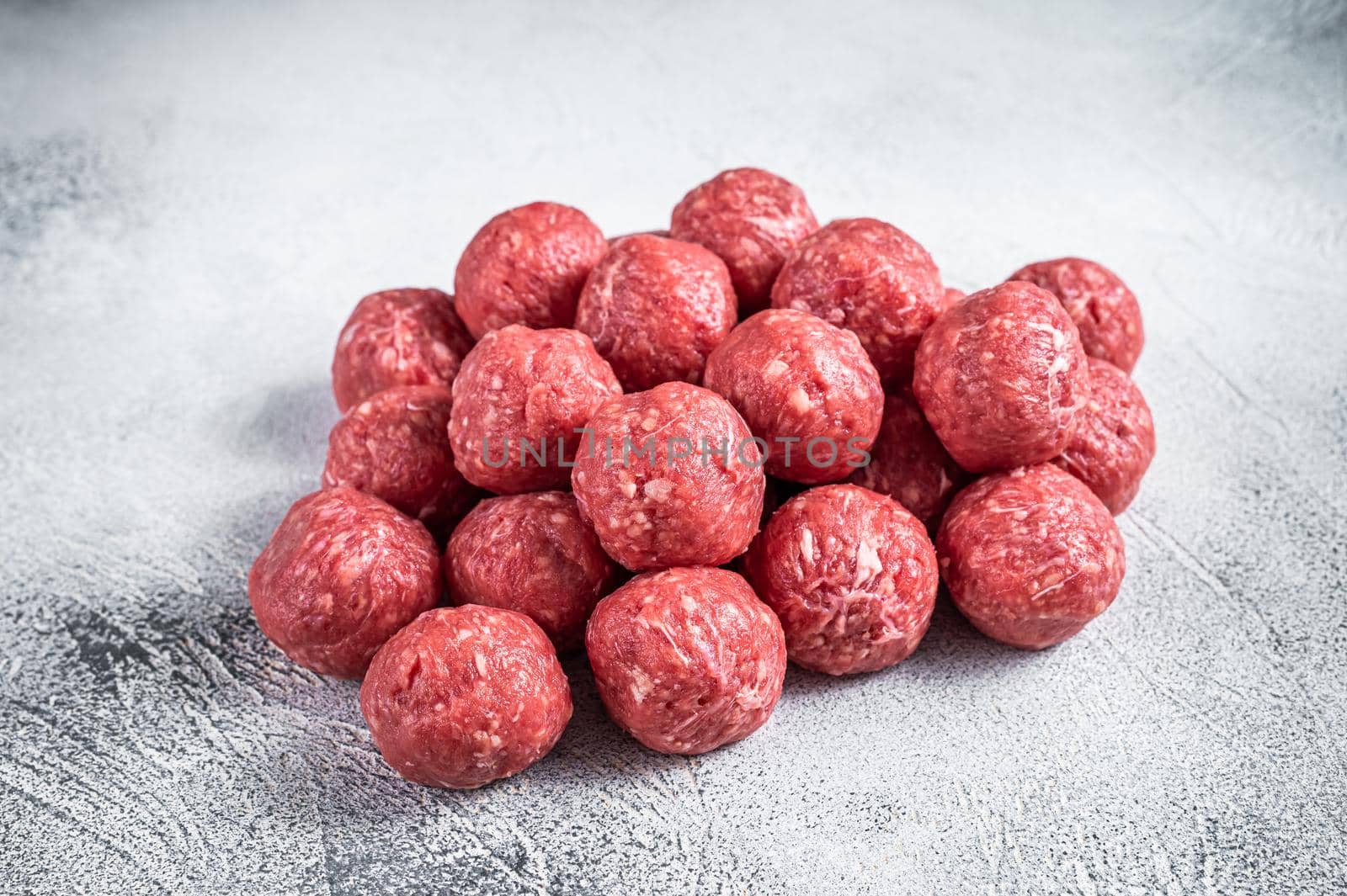 Raw beef and pork meatballs with spices on kitchen table. White background. Top view.