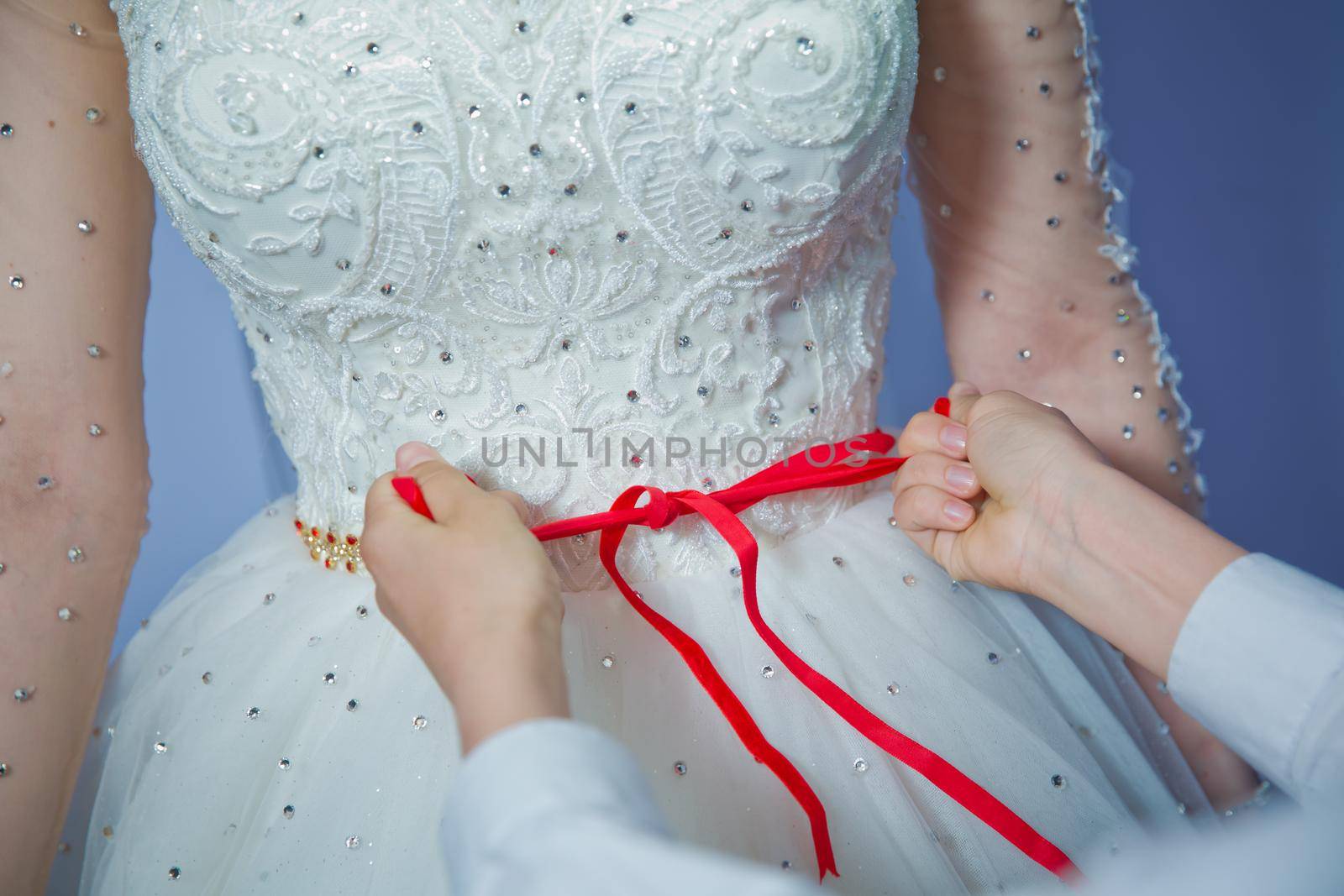 Wedding . Bridesmaids lace bride . Close the ribbon on the belly the bride . Close the ribbon on the belly of the bride . Lose the ribbon on the belly of the bride . by Adil_Celebiyev_Stok_Photo