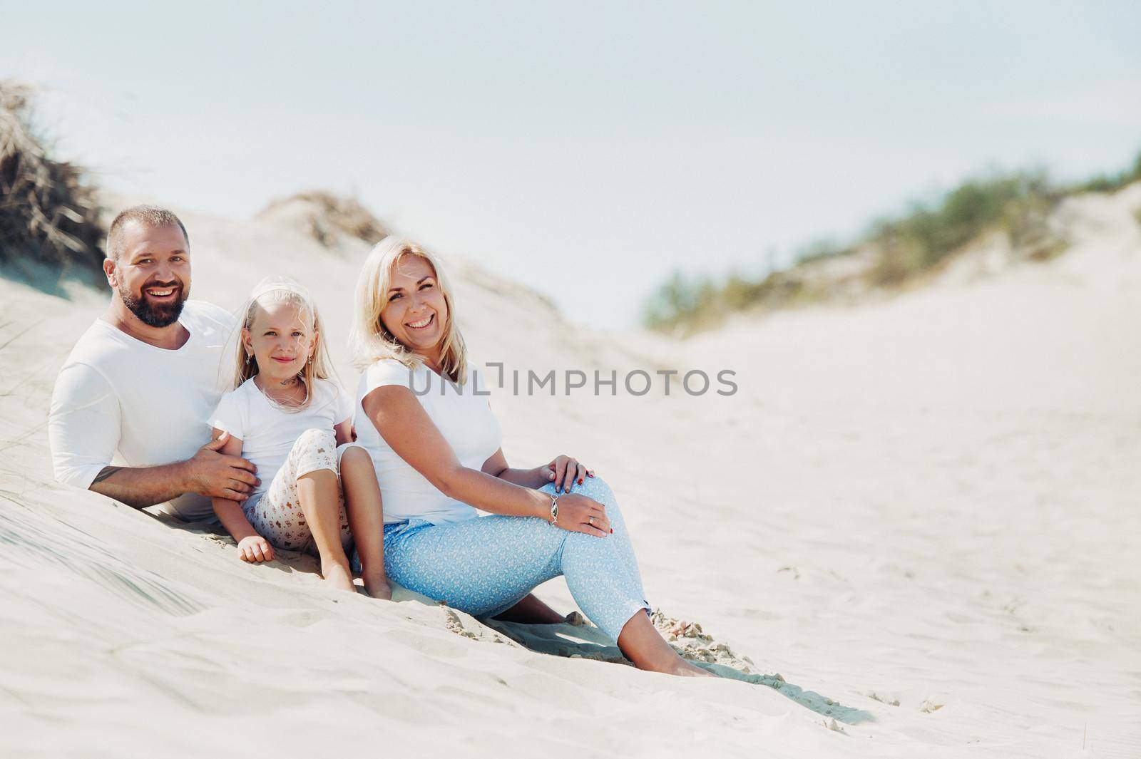 A happy family of three on the sand dunes of the Baltic sea near the city of Nida.Family trip to Europe.Lithuania.