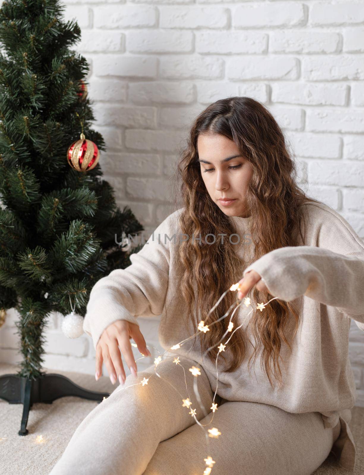 Merry christmas and happy new year. young attractive woman decorating the Christmas tree with fairy lights