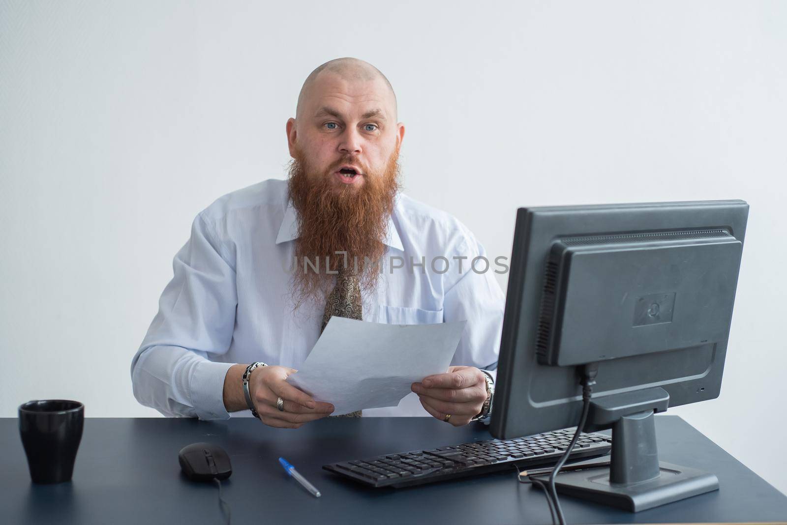 Portrait of a bald man at a desk looking at a report and cursing. The dissatisfied boss dismisses the subordinate