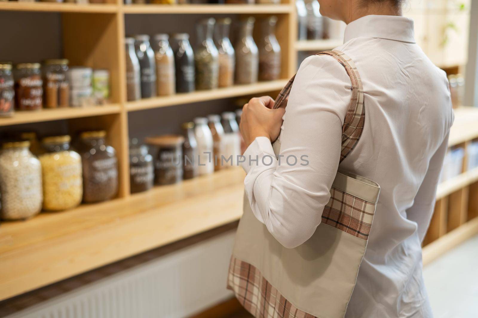 Woman in a store selling cereals by weight in an eco store. Trade concept without plastic packaging by mrwed54