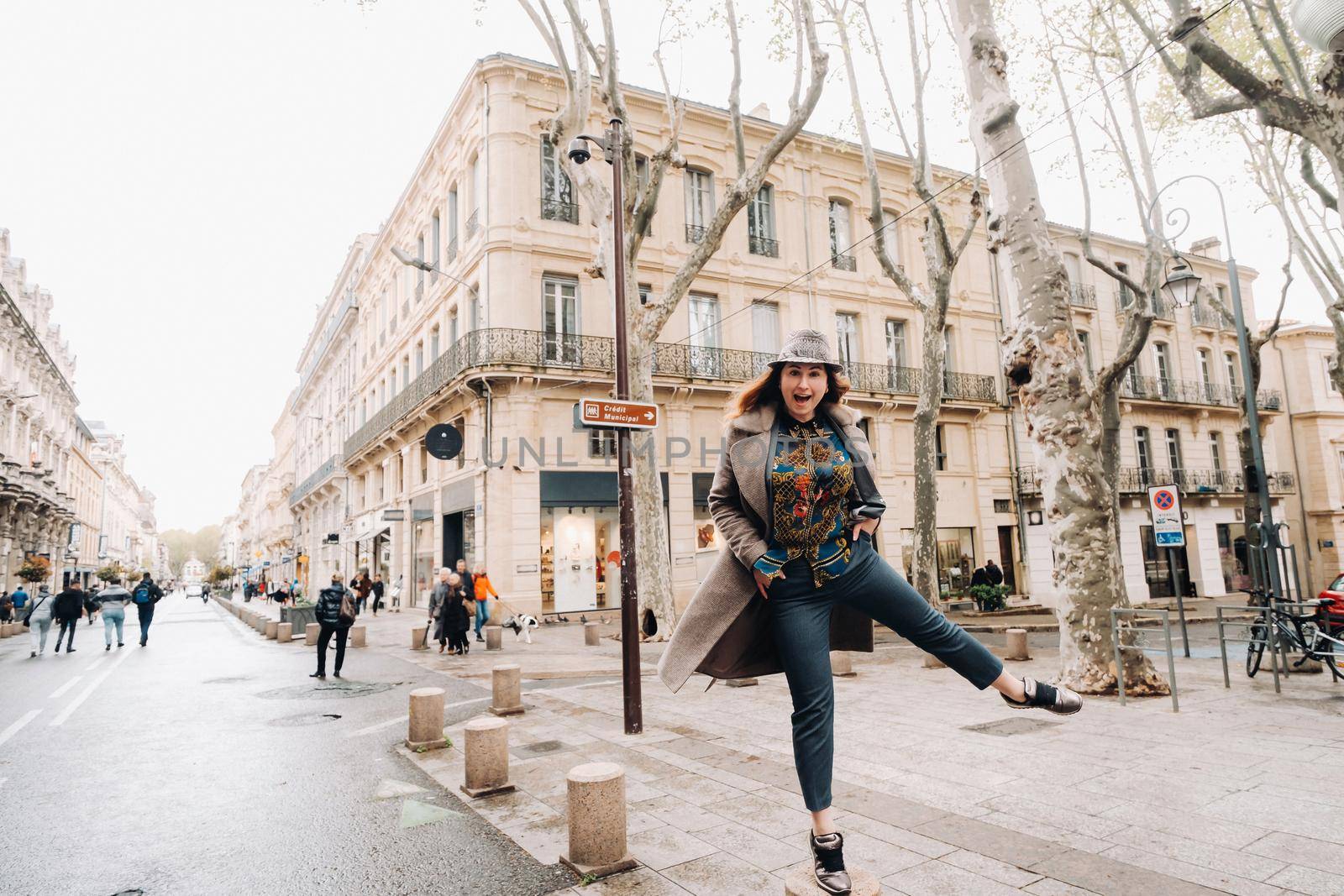 a beautiful romantic girl in a coat with her hair down runs through the old city of Avignon. France. Girl in a coat in France.