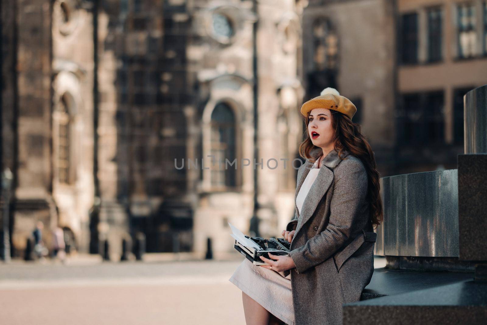 a stylish young beautiful girl is sitting and typing in the Old town of Dresden.Germany