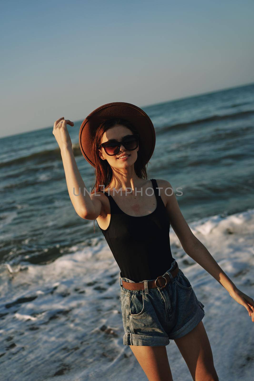 cheerful woman in sunglasses and a hat by the ocean walk summer. High quality photo
