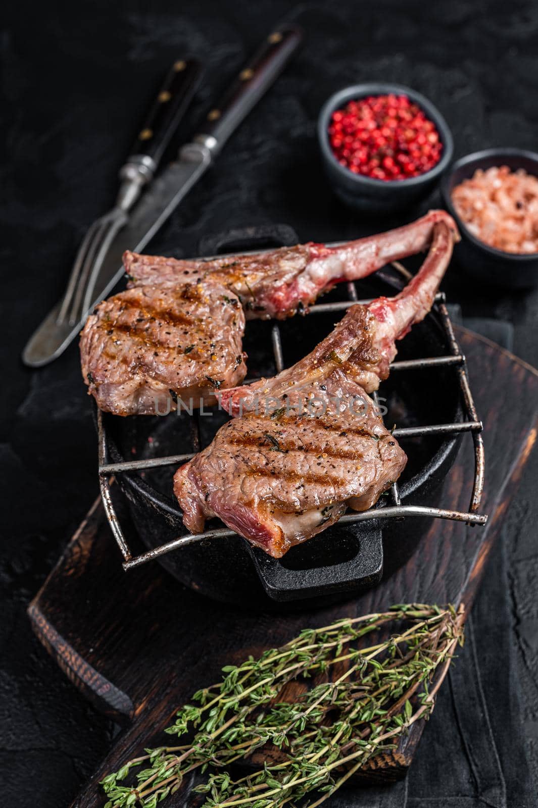 Grilled lamb mutton meat chops steaks on a grill. Black background. Top view by Composter
