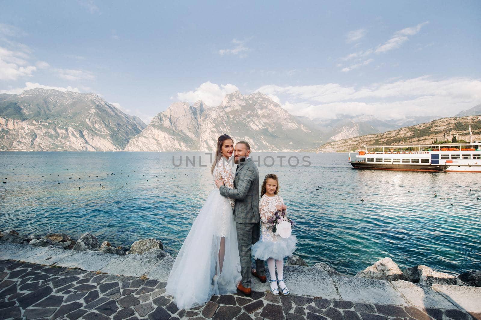 Italy, Lake Garda. Beautiful family on the shores of lake Garda in Italy at the foot of the Alps. Father, mother and daughter in Italy.