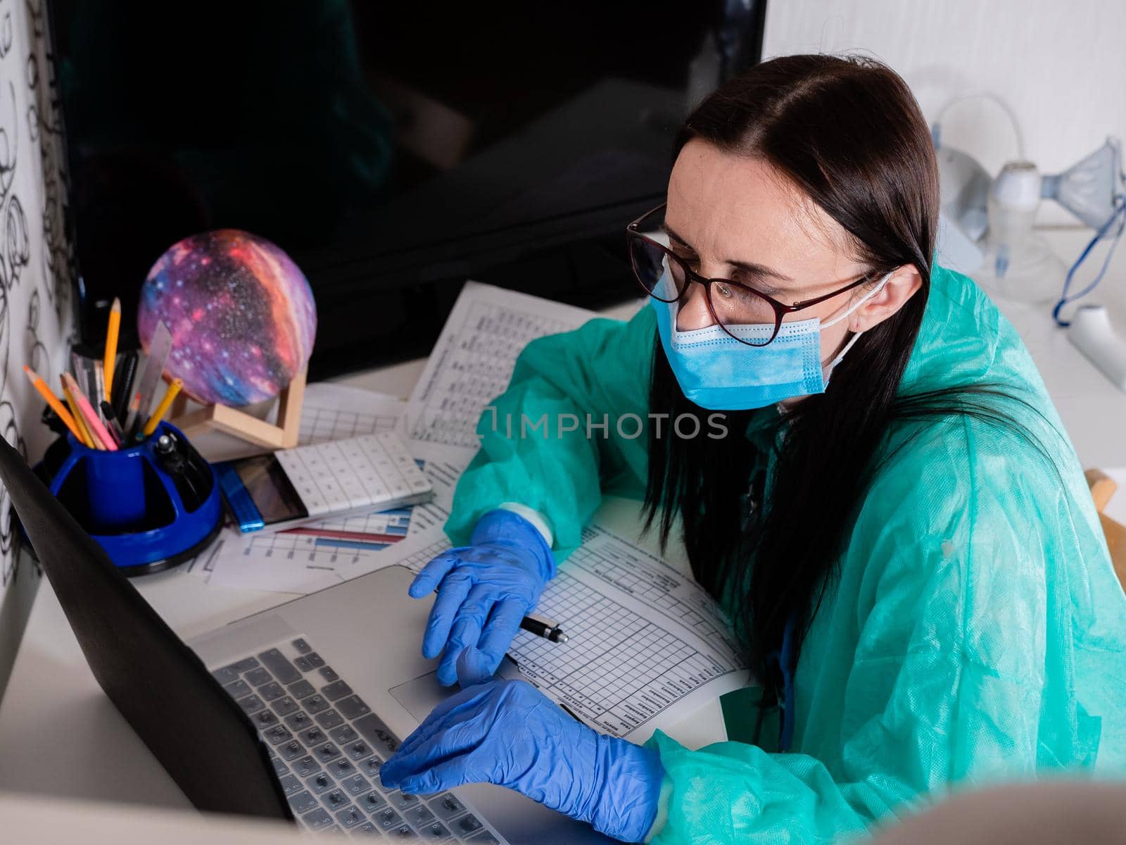 Female doctor in medical mask works with the computer.