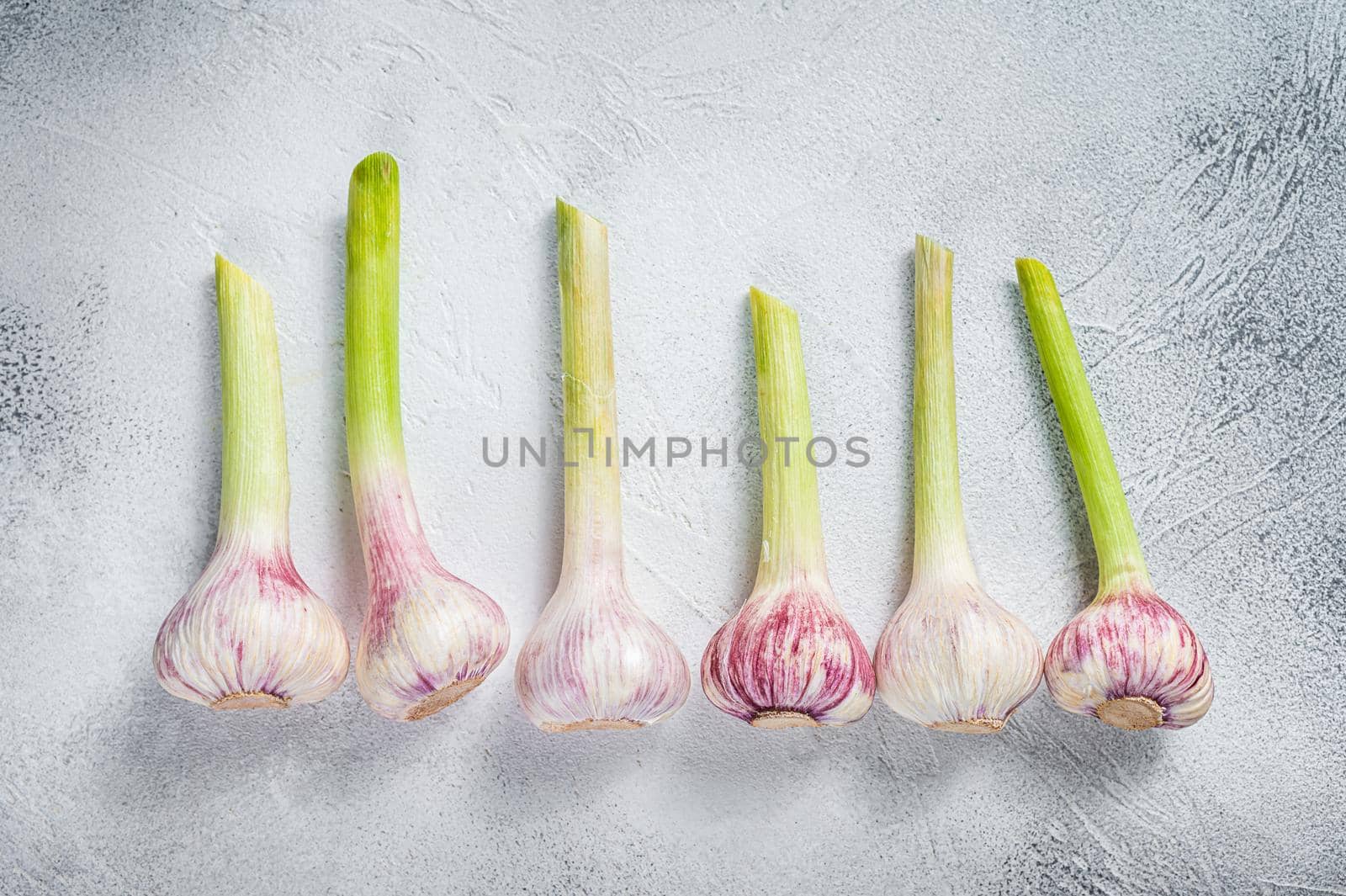 Spring young garlic bulbs on kitchen table. White background. Top view.