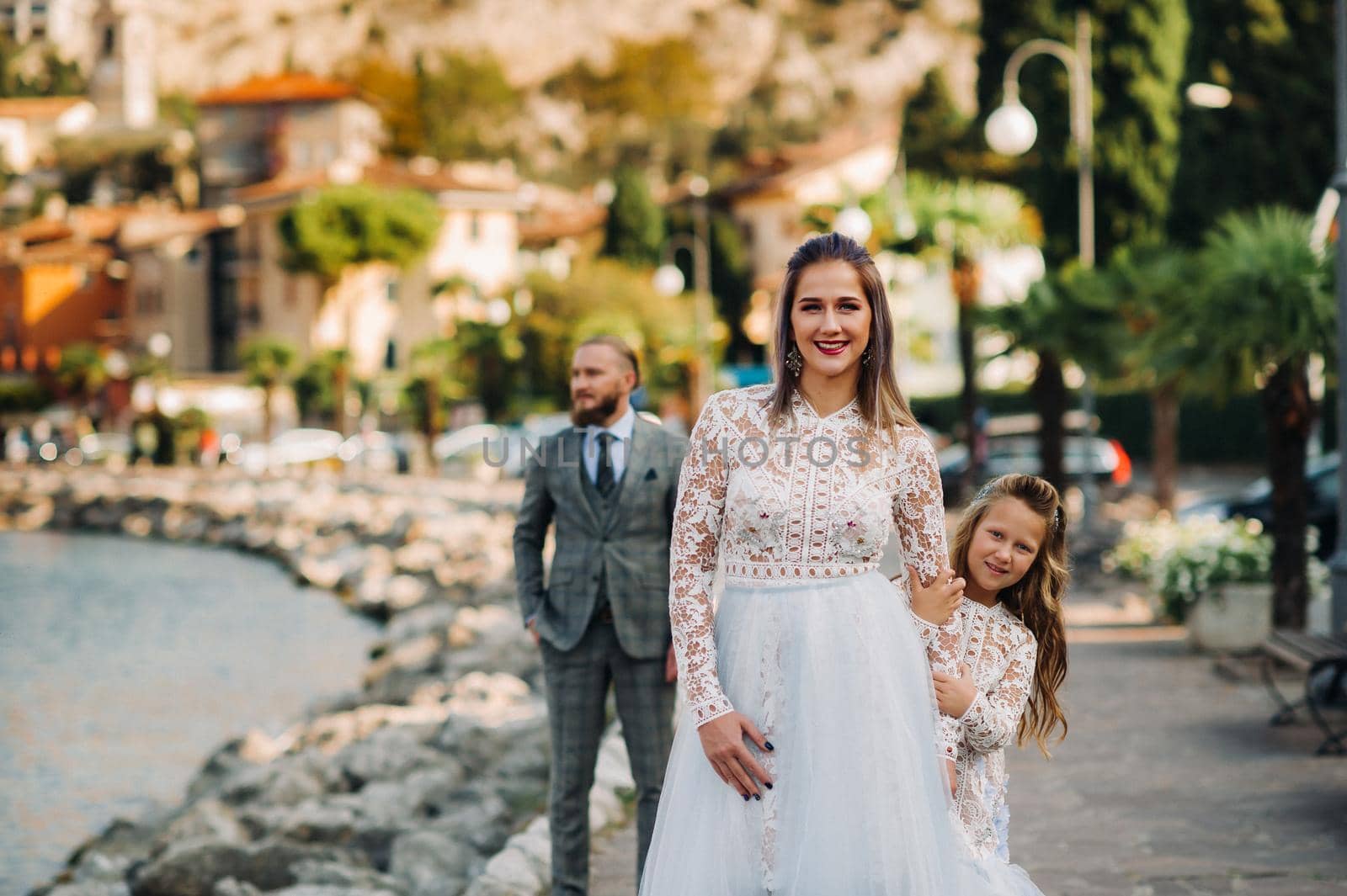 Italy, Lake Garda. Beautiful family on the shores of lake Garda in Italy at the foot of the Alps. Father, mother and daughter in Italy by Lobachad