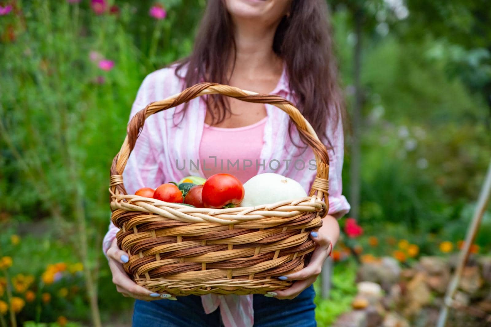 faceless happy smiling woman farmer holding a basket of vegetables from her vegetable garden. close up no face