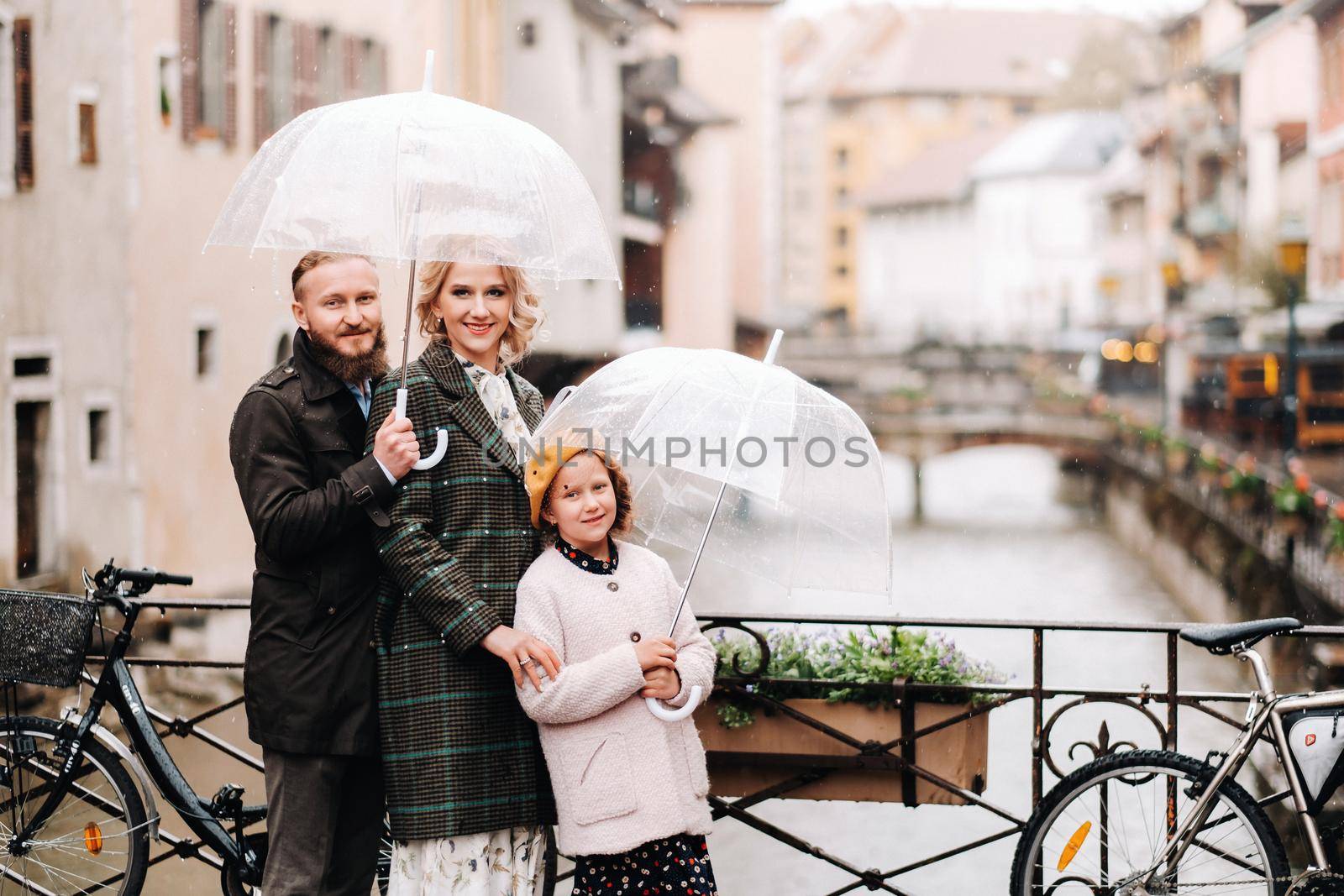 Beautiful family with umbrellas in rainy weather in Annecy. France.Family walk in the rain.